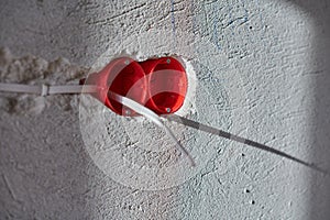 Plastic socket box and electrical wires on plastered wall