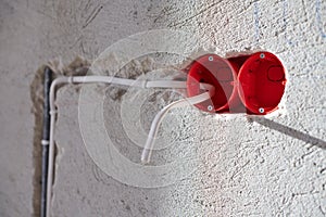 Plastic socket box and electrical wires on plastered wall