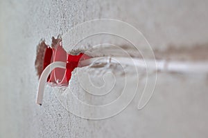 Plastic socket box and electrical wires on plastered wall