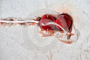 Plastic socket box and electrical wires on plastered wall