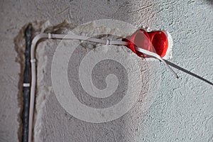 Plastic socket box and electrical wires on plastered wall