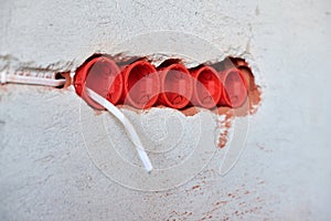 Plastic socket boxes and electrical wires on plastered wall