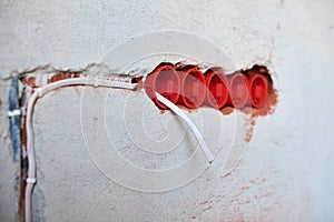 Plastic socket boxes and electrical wires on plastered wall