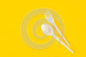 Plastic spoon and fork on yellow background