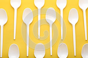 Plastic spoons on color background, top view.