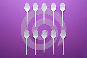 Plastic spoons on color background, top view