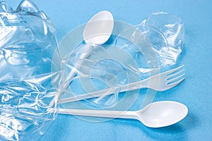 Plastic spoons, forks and cups as a disposable waste with copy space on bright blue background. Environmental pollution and litter