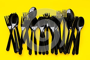 Plastic spoons and forks utilization and the Earth protection concept with flatware on yellow background top view