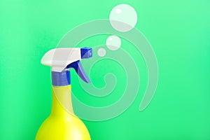 Plastic spray yellow bottle isolated on green background and painted soap bubbles