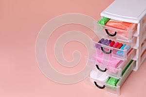 Plastic storage drawers with menstrual pads and tampons on pink background, closeup. Space for text