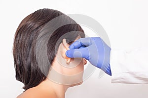 A plastic surgeon doctor examines a patient s girl s ears before performing an otoplasty surgery, close-up