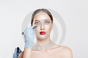 Plastic surgery concept. Doctor Hands drawing marks on female face against white grey background. Facial Treatment. Portrait Of Be
