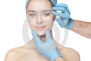 Plastic surgery concept. Doctor hands in gloves touching woman face