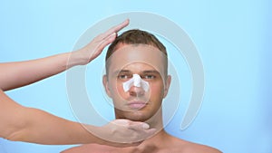 Plastic surgery concept, hands holding a man`s face. a man after a plastic surgery on the face, rhinoplasty , with a photo