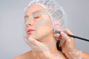 Plastic surgery. Doctor drawing perforation lines on woman`s face