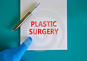 Plastic surgery symbol. White note with words Plastic surgery, beautiful blue background, doctor hand in blu glove and metallic