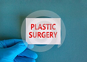 Plastic surgery symbol. White note with words Plastic surgery, beautiful blue background, doctor hand in blue glove. Medical and