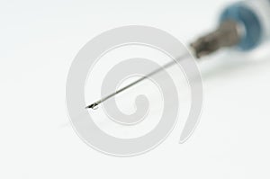 Plastic syringe with needle, focus on the liquid drop.