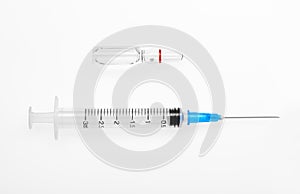 Plastic syringe with open needle and transparent white glass ampoule with a drug