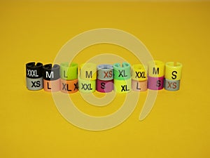 Plastic tags of clothing sizes for the store. Isolated on a yellow background.