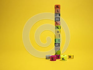 Plastic tags of clothing sizes for the store. Isolated on a yellow background.