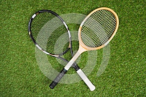 Plastic tennis and wooden badminton rackets on green lawn