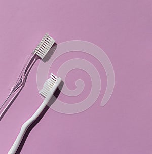 Plastic toothbrushes on the bright violet background. Top view.