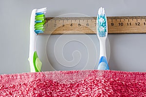 Plastic toothbrushes lie on the ruler under the towel