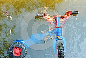 Plastic toy bike as wastes on river bed