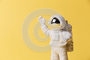 Plastic toy figure astronaut on a yellow background. Copy space. Close-up