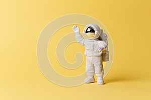 Plastic toy figure astronaut on a yellow background. Copy space. Close-up. The concept of space and space flights