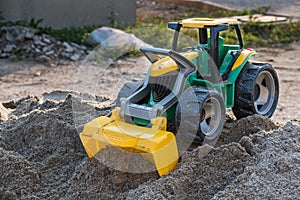 Plastic toy front loader on the sand pile