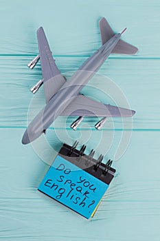 Plastic toy passenger jet plane and sticky paper on blue wooden background.