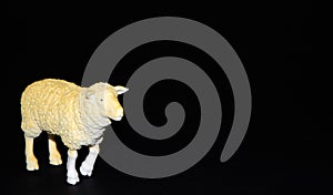 Plastic toy sheep on a black background. Realistic toy Copy Space