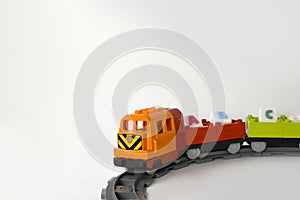 Plastic toy train with letters on railroad on white background.