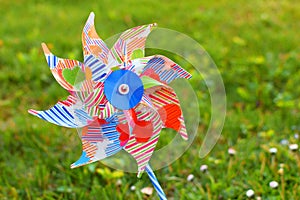 Plastic toy windmill  turbine on green blurred grass background