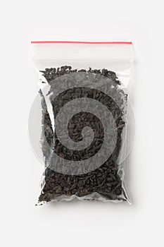 Plastic transparent zipper bag with full of black tea isolated on white, Vacuum package mockup with red clip. Concept