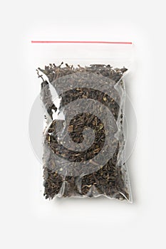 Plastic transparent zipper bag with full of dried darjeeling black tea isolated on white, Vacuum package mockup with red clip. Con