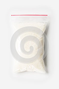 Plastic transparent zipper bag with full Granulated sugar isolated on white, Vacuum package mockup with red clip. Concept.