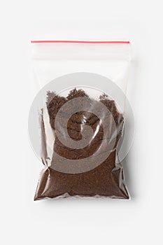 Plastic transparent zipper bag with half Brewed coffee powder isolated on white, Vacuum package mockup with red clip. Concept