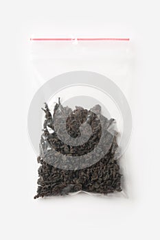 Plastic transparent zipper bag with halfblack tea isolated on white, Vacuum package mockup with red clip. Concept.