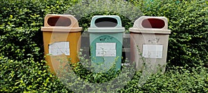 a plastic trash can installed in a park, close up view