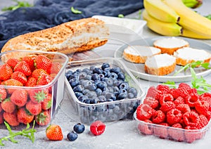 Plastic tray containers of fresh organic healthy beries and bread for fruit sandwiches. Blueberries, strawberries, bananas and ras