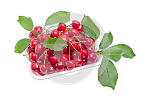 Plastic tray with sweet cherries and branches with leaves