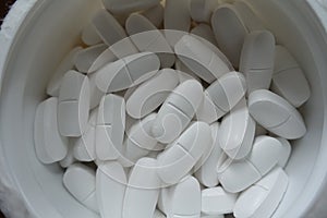 Plastic tub filled with white caplets from above