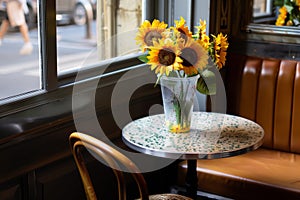 a plastic vase with faux sunflowers on a small bistro table in a caf corner photo