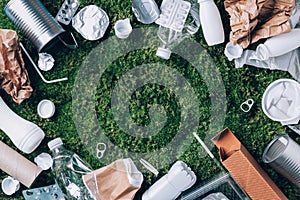 Plastic waste, food packaging, trash collection on green moss background after picnic in forest. Plastic free. Top view