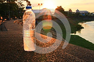 Plastic water bottle on the stone floor in a public park at sunset, sunrise time