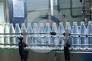 Plastic water bottles on conveyor and water bottling machine industry.