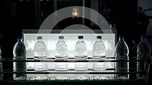 Plastic water bottles on conveyor and water bottling machine industry.